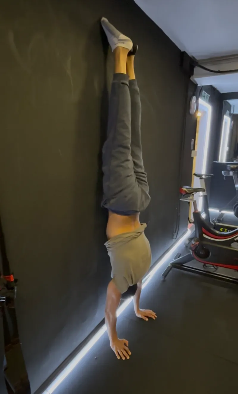 Client performing handstand in a gym