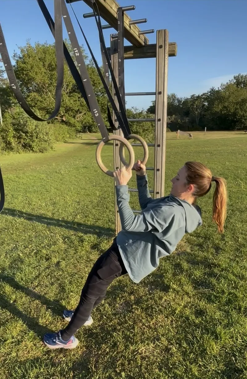 Client performing ring rows in golden hour light